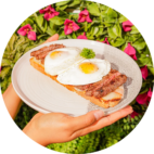 Colombian brunch dish with fried eggs bacon and fresh salad garnish